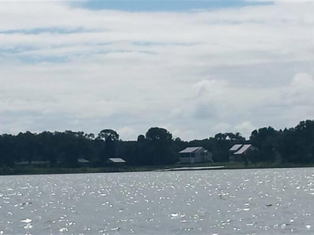 View of Lake Weir with houses and trees along the shoreline under a partly cloudy sky