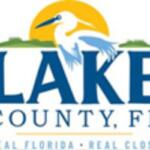 Orange sun at top in the background, great blue heron, with green sod on either side. Underneath the bird, lettering with the fons size getting smaller as it gets lower on the page.