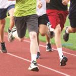 Close-up of runners' legs as they race on a red track.