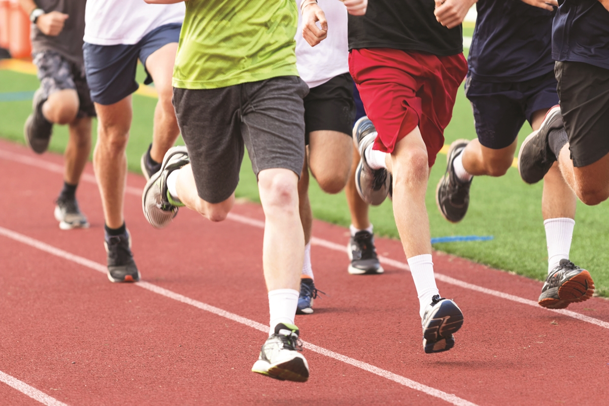 Close-up of runners' legs as they race on a red track.