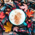A pumpkin spice latte mug surrounded by fall leaves.