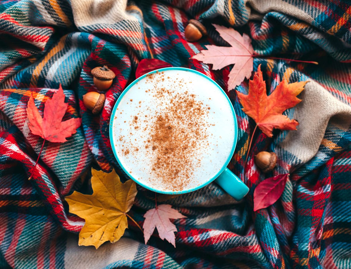 A pumpkin spice latte mug surrounded by fall leaves.