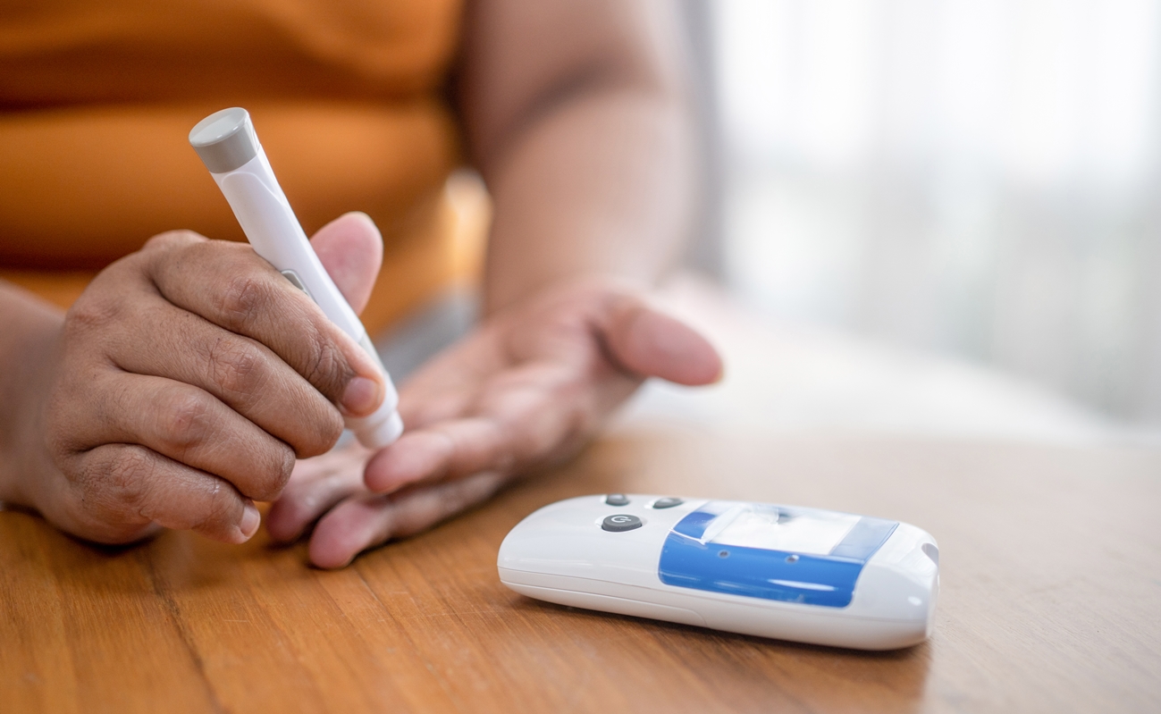 Close-up of a person using a glucose monitor to check blood sugar levels.