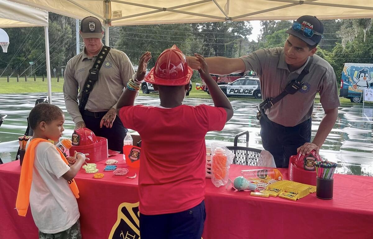 Firefighters give toy helmets and safety items to children at Ocala’s National Night Out event.