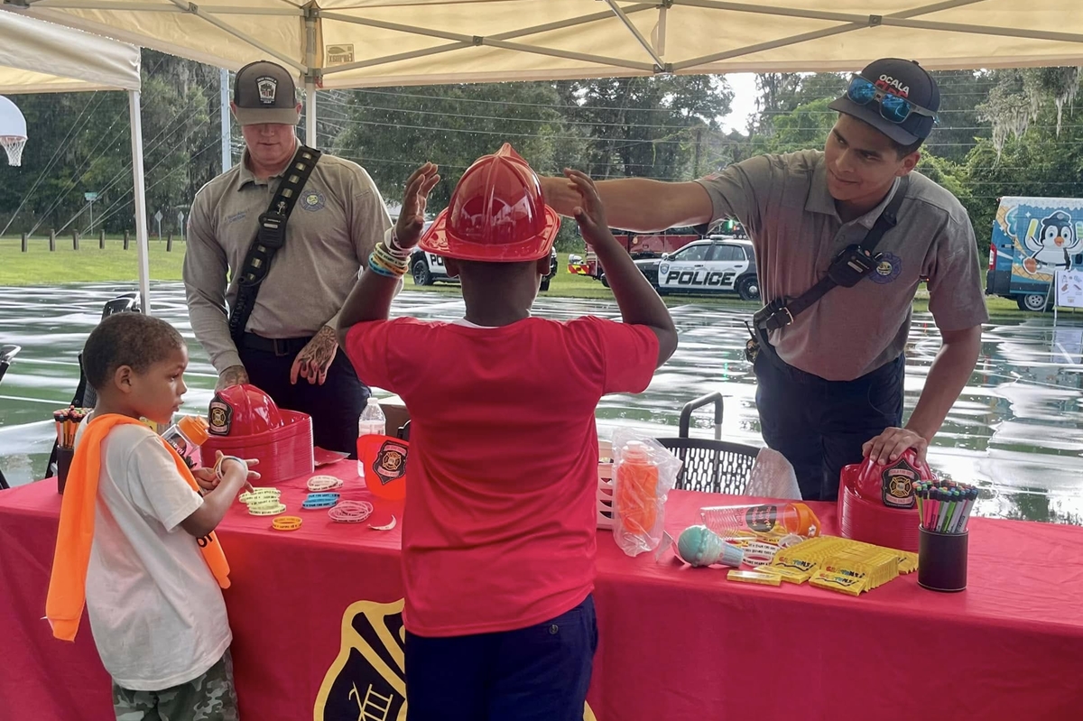 Firefighters give toy helmets and safety items to children at Ocala’s National Night Out event.
