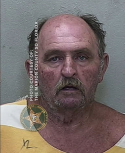 Mugshot of Roger Childers, a balding man with a gray mustache and beard stubble, wearing a white-and-orange jail uniform, looking directly at the camera with a serious expression.