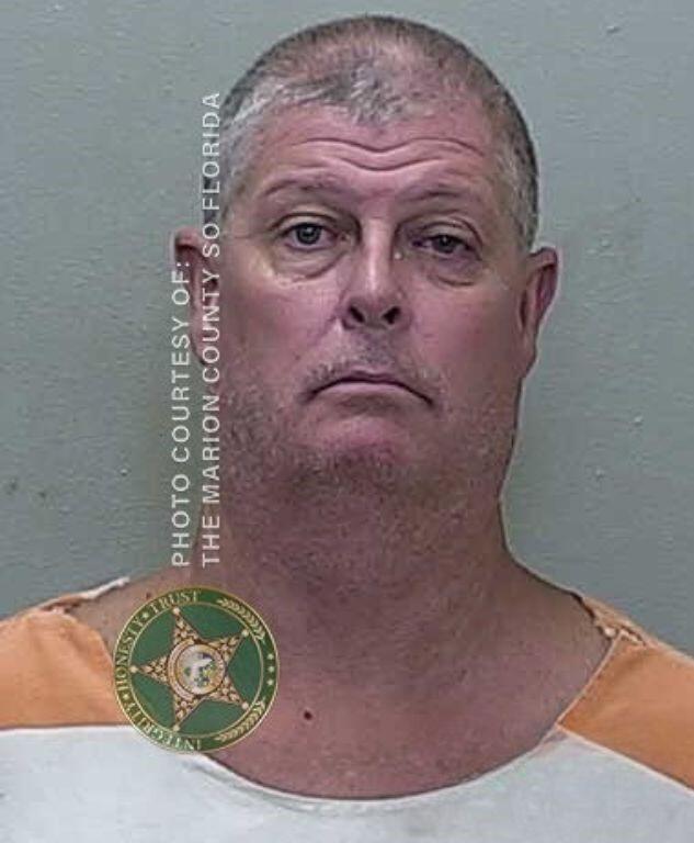 Mugshot of a man in an orange-and-white jail uniform, looking at the camera with a blank expression.