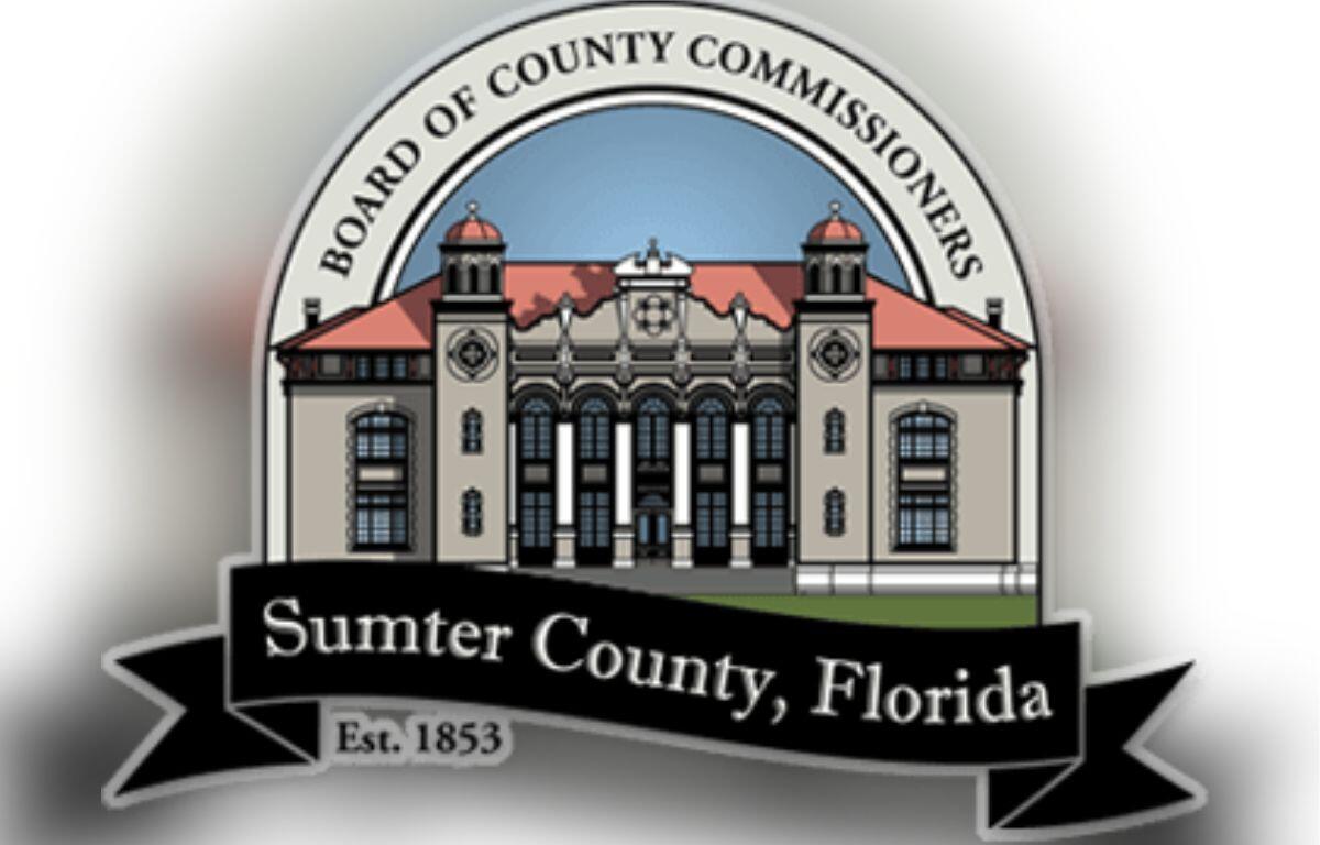 A logo with an arc over top of an image of a building, with lettering in the arc. Below the building, there is a flag banner with writing.