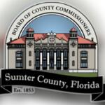 A logo with an arc over top of an image of a building, with lettering in the arc. Below the building, there is a flag banner with writing.