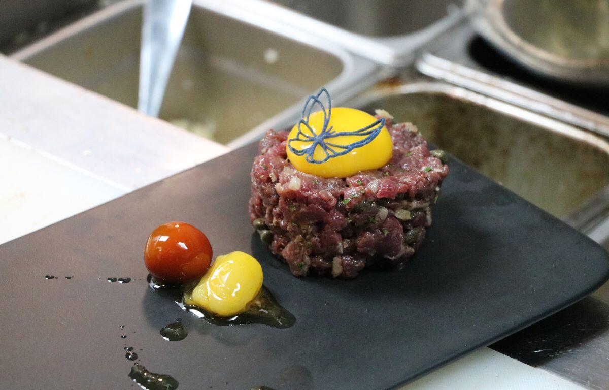 Stacked entrée with layered ingredients and colorful garnish.