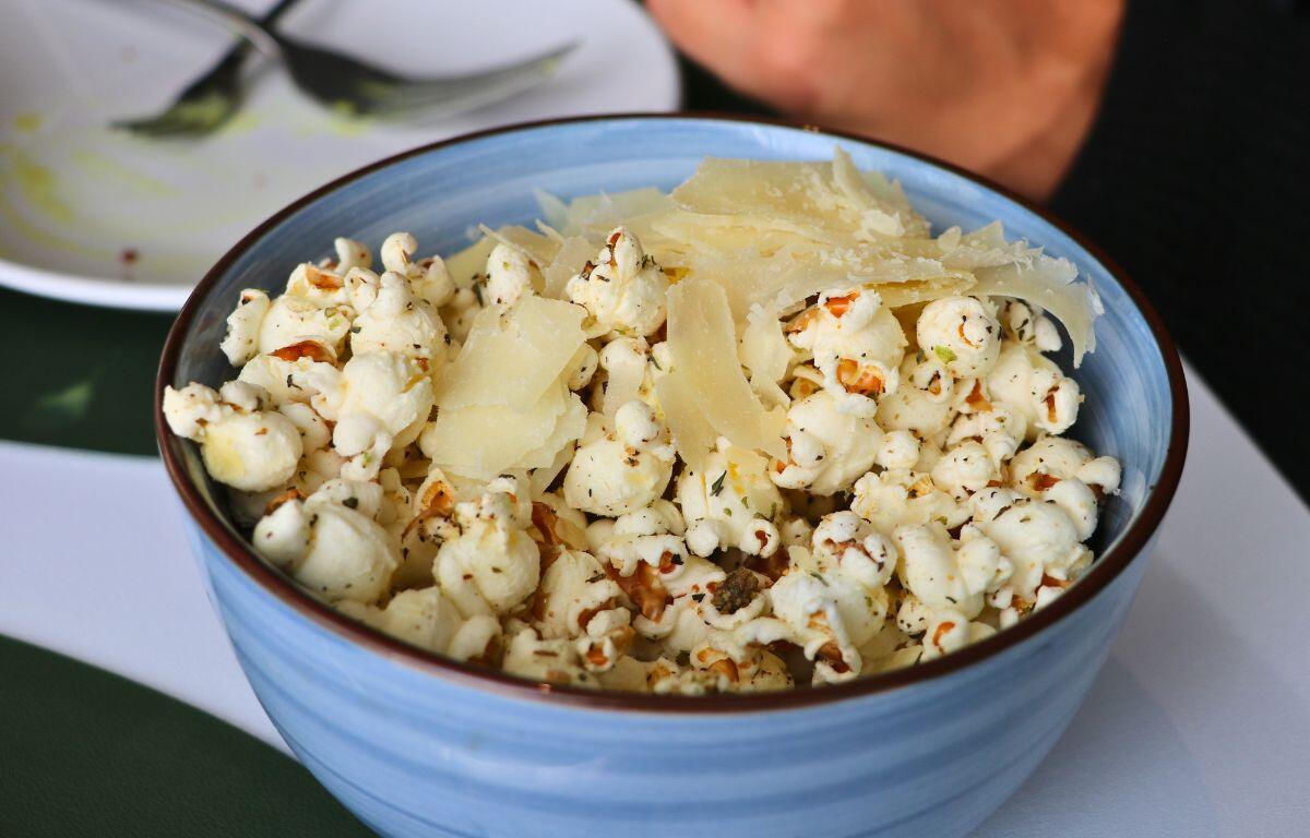 Bowl of freshly popped popcorn topped with cheese and truffle.