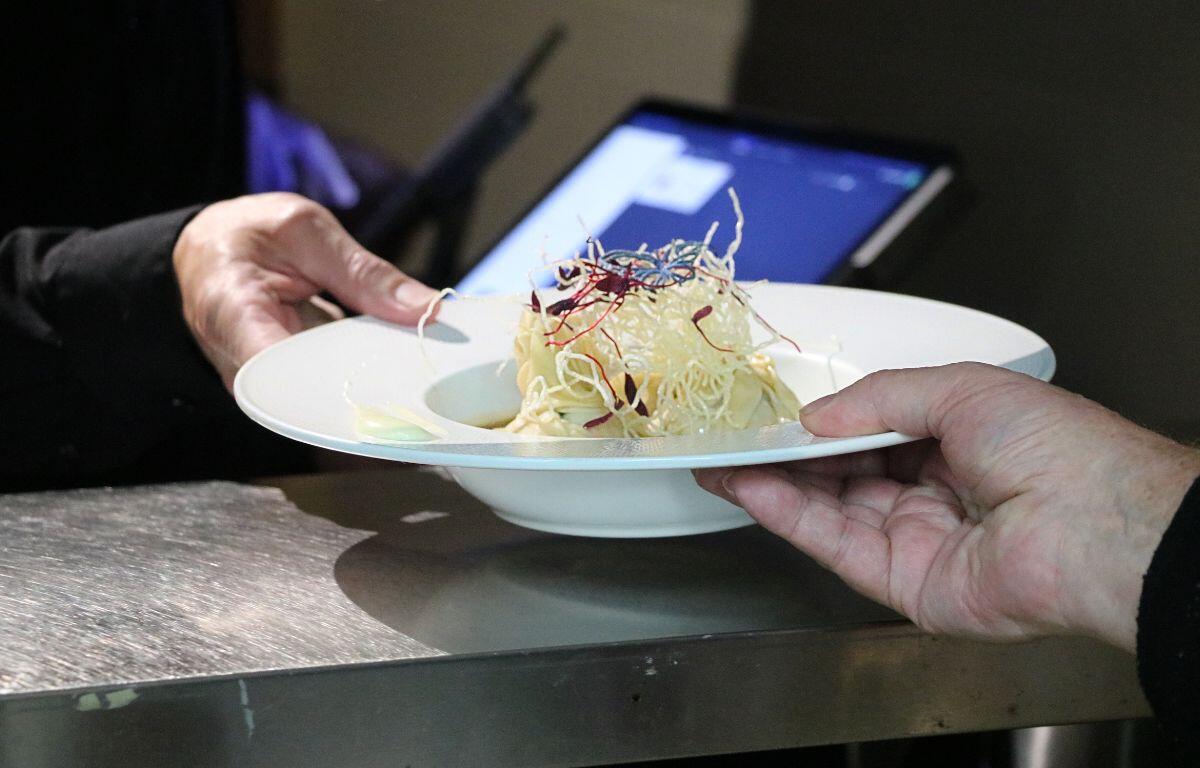 Hands holding a wrapped handheld entrée on a plate.