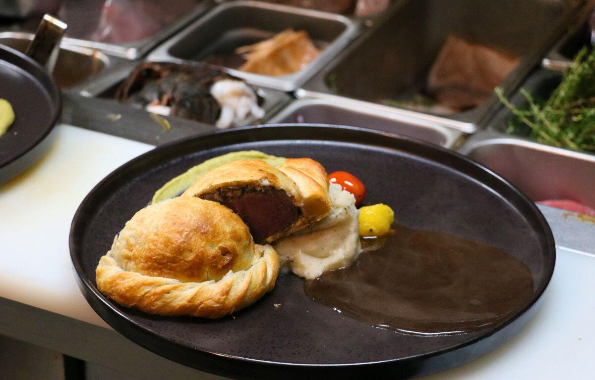 Beef Wellington sliced to reveal tender beef inside golden puff pastry, served on a black plate.