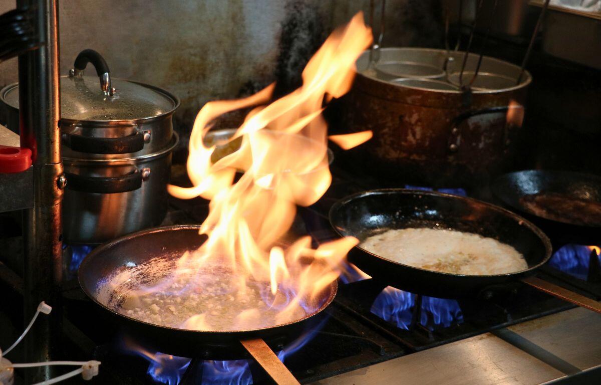 Flames rise from a skillet while cooking.