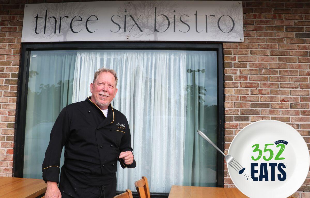 A man in a black chef's uniform standing in front of a brick-front underneath a sign that reads, "Three Six Bistro".