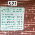 Glass door to the left, bring wall with a numbers on a placard above large placard with letters and numbers.