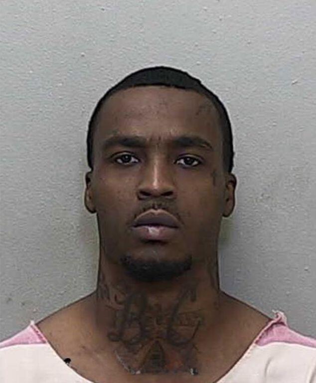 Mugshot of an African American man with short hair and a goatee in an orange and white jumpsuit.