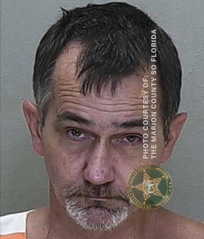 Mugshot of Brian Jordling, wearing a white and orange jail uniform, photographed against a gray background.