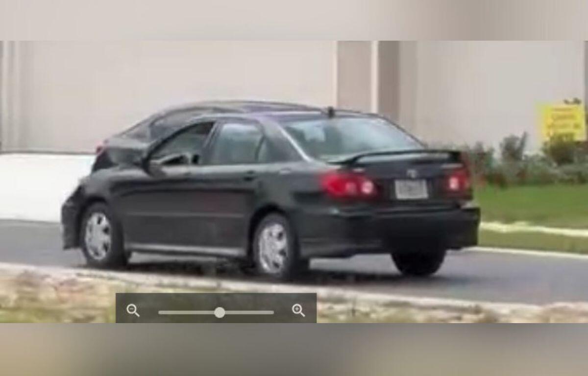 A black sedan parked on the side of a suburban street.