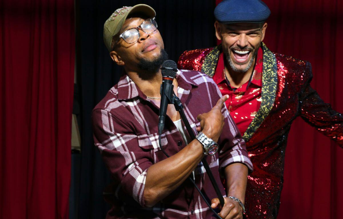 Two performers stand together onstage during the show’s closing, smiling as the night winds down.