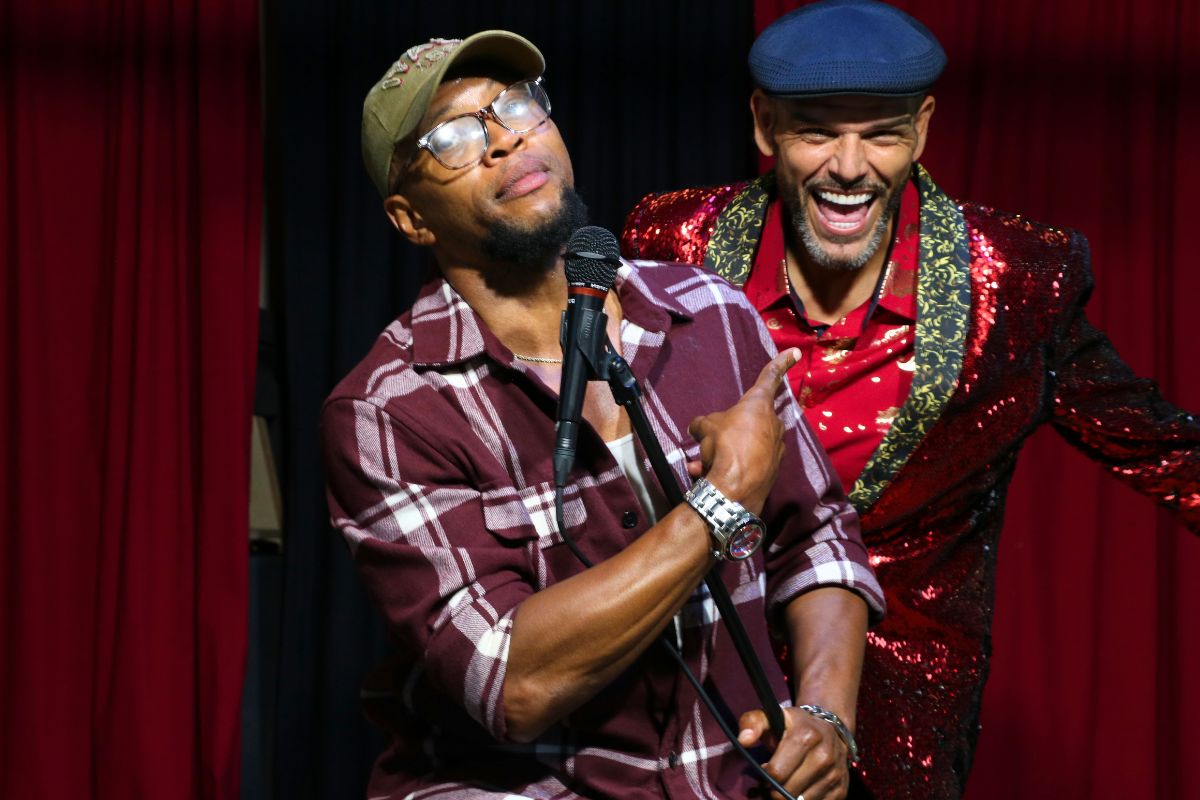 Two performers stand together onstage during the show’s closing, smiling as the night winds down.