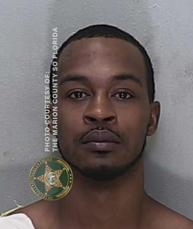 Mugshot of Jeremy Flowers, wearing a white jail uniform, photographed against a gray background.