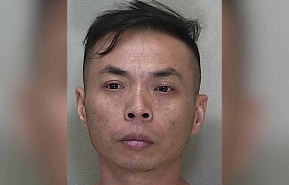 A man standing against a gray wall.