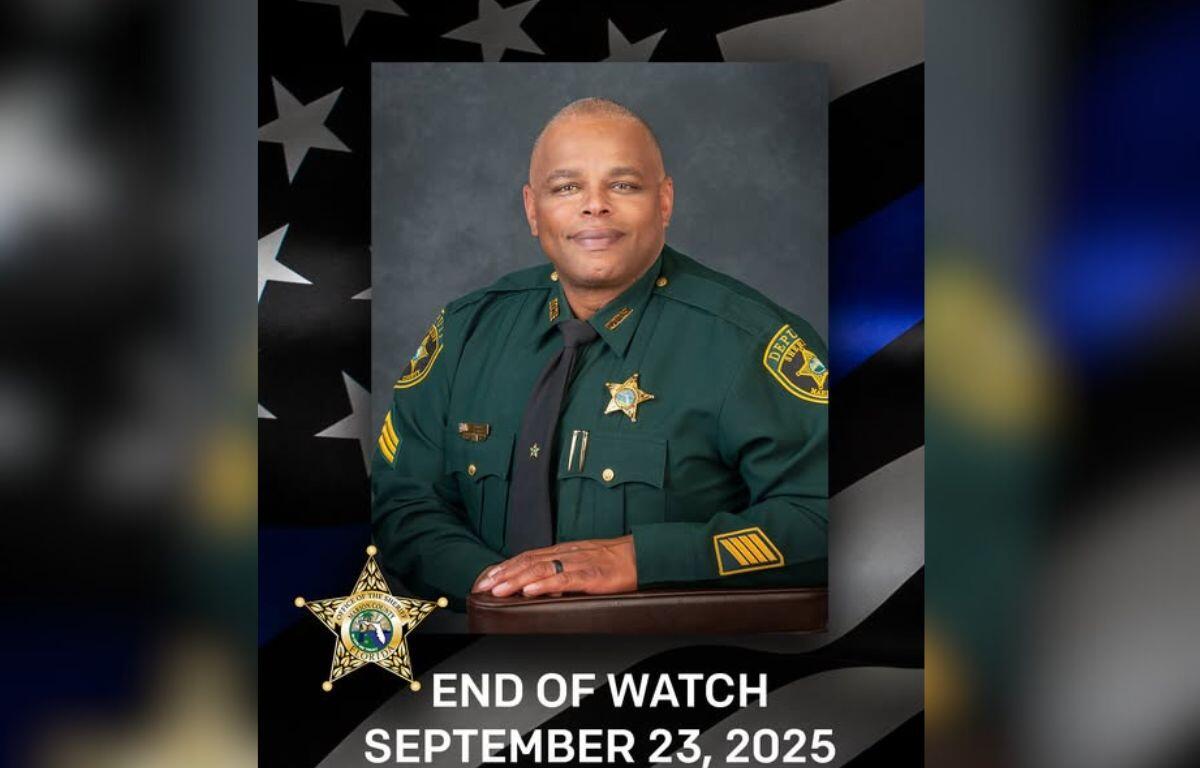 A gentleman in his green law enforcement uniform, with an American flag to his left, and letter and numbers at the bottom of the image.