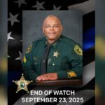A gentleman in his green law enforcement uniform, with an American flag to his left, and letter and numbers at the bottom of the image.