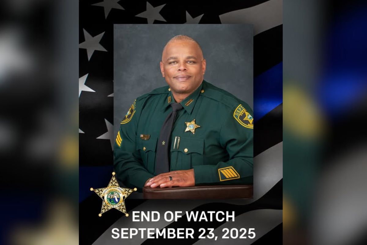 A gentleman in his green law enforcement uniform, with an American flag to his left, and letter and numbers at the bottom of the image.