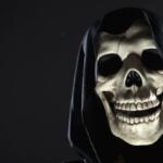 A cloaked skull peeking out of the shadows against a dark background.