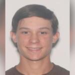 Headshot of 17-year-old Caden Speight, smiling, with short brown hair, wearing a dark shirt, against a plain light background.