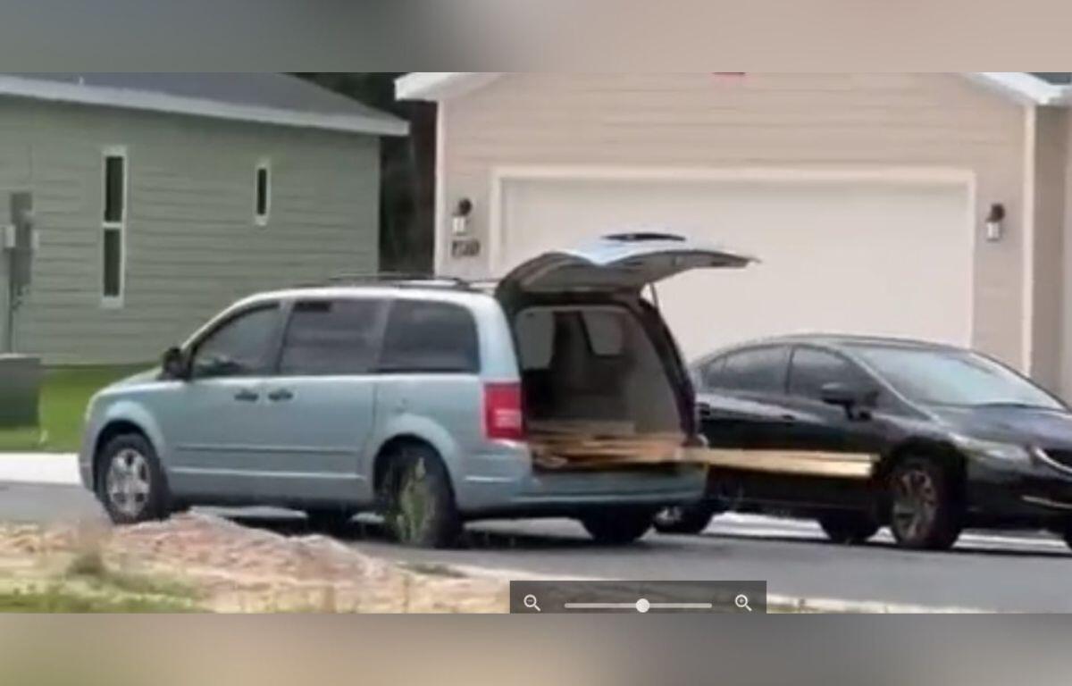 A gray van with its rear hatch open, parked in front of a house.