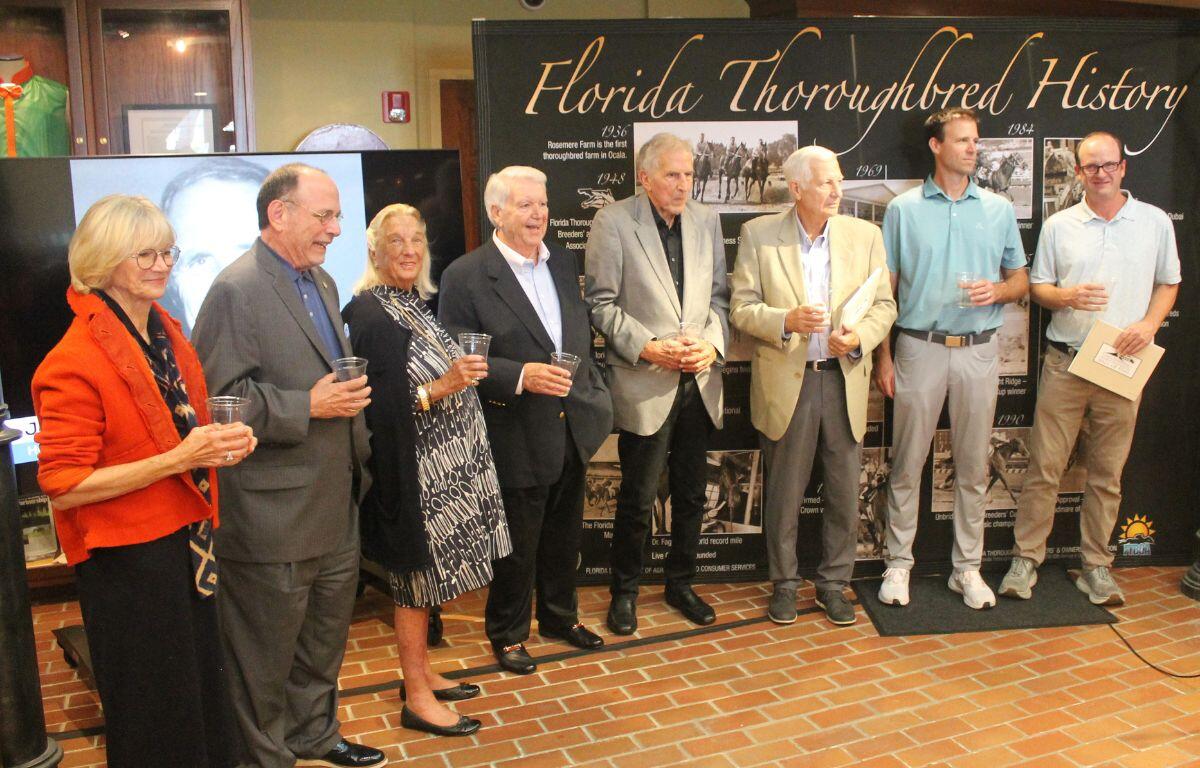 A group of people standing in front of an exhibit placard, with a faux brick floor in the foreground.