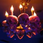 A lit chandelier decorated with skulls in a darkened room.