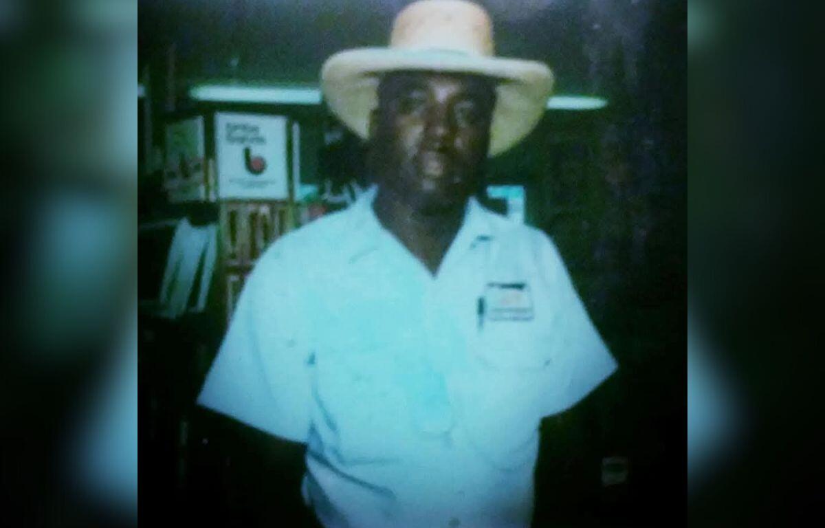 Items in the background on both the left and right. A man standing in the center wearing a hat.