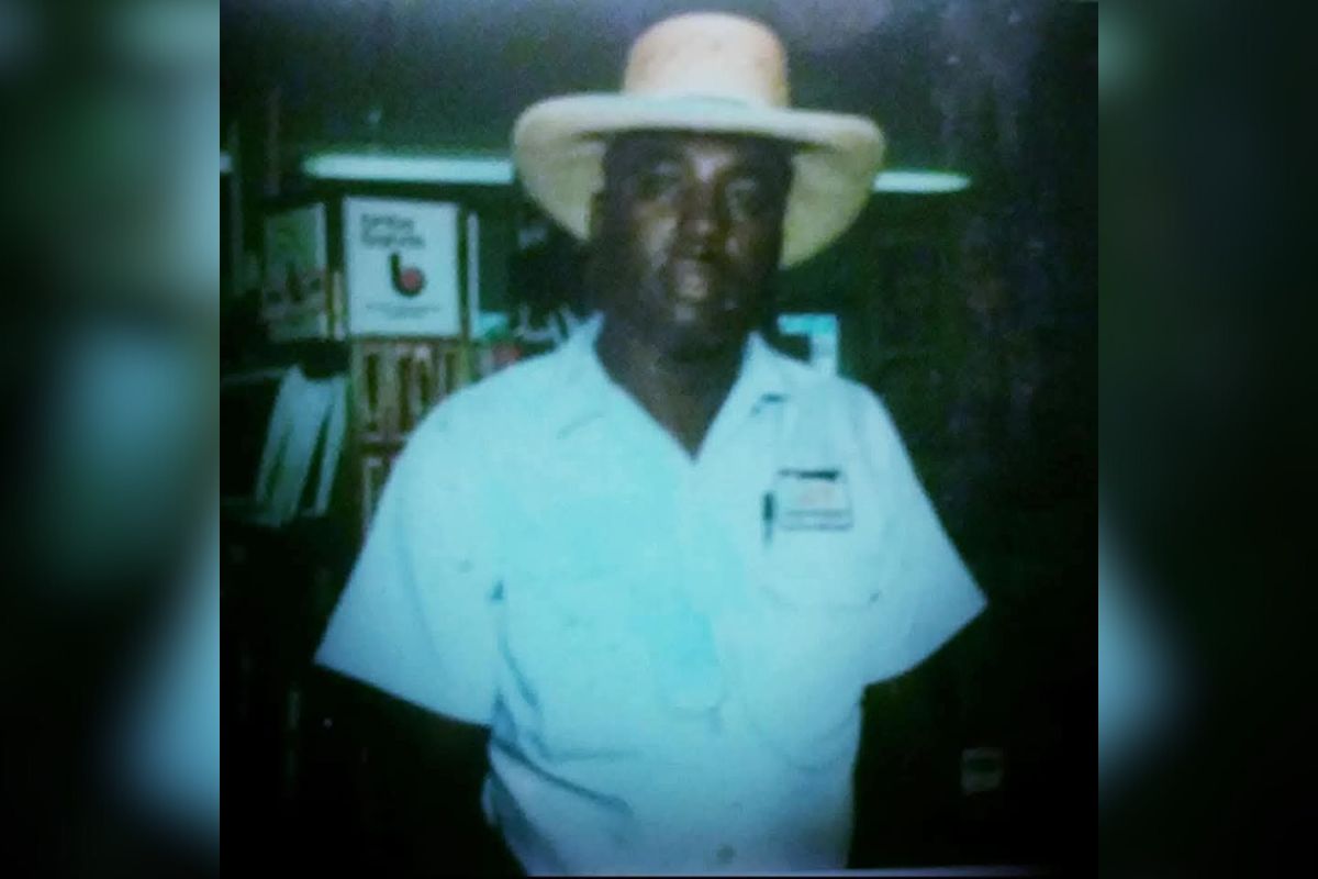 Items in the background on both the left and right. A man standing in the center wearing a hat.