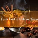 A warm holiday scene with a steaming simmer pot filled with sliced oranges, cinnamon sticks, and star anise on a wooden surface, surrounded by spices, a lit tealight candle, and a ladle, with a banner reading “A Fresh Twist of Holiday Warmth.”