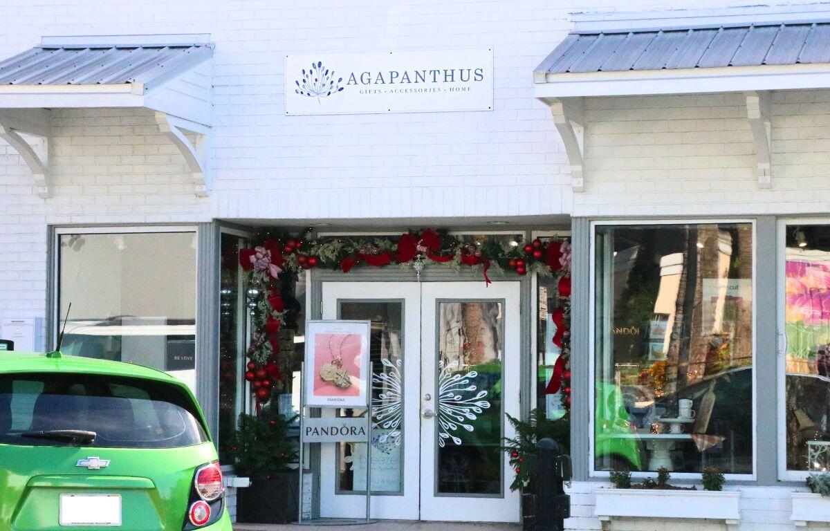A beige storefront has white overhangs with gray tops. The storefront has Christmas decorations and a white sign above it that reads, "Agapanthus."
