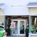 A beige storefront has white overhangs with gray tops. The storefront has Christmas decorations and a white sign above it that reads, "Agapanthus."