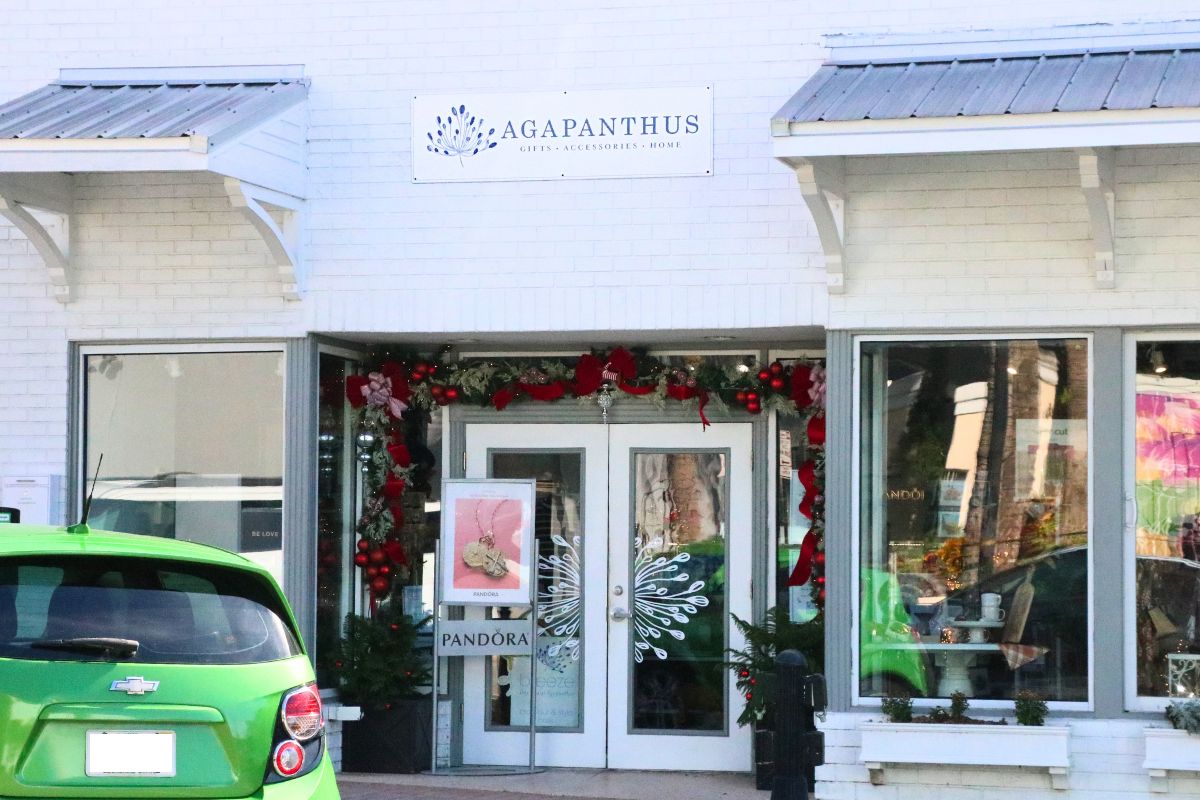 A beige storefront has white overhangs with gray tops. The storefront has Christmas decorations and a white sign above it that reads, "Agapanthus."