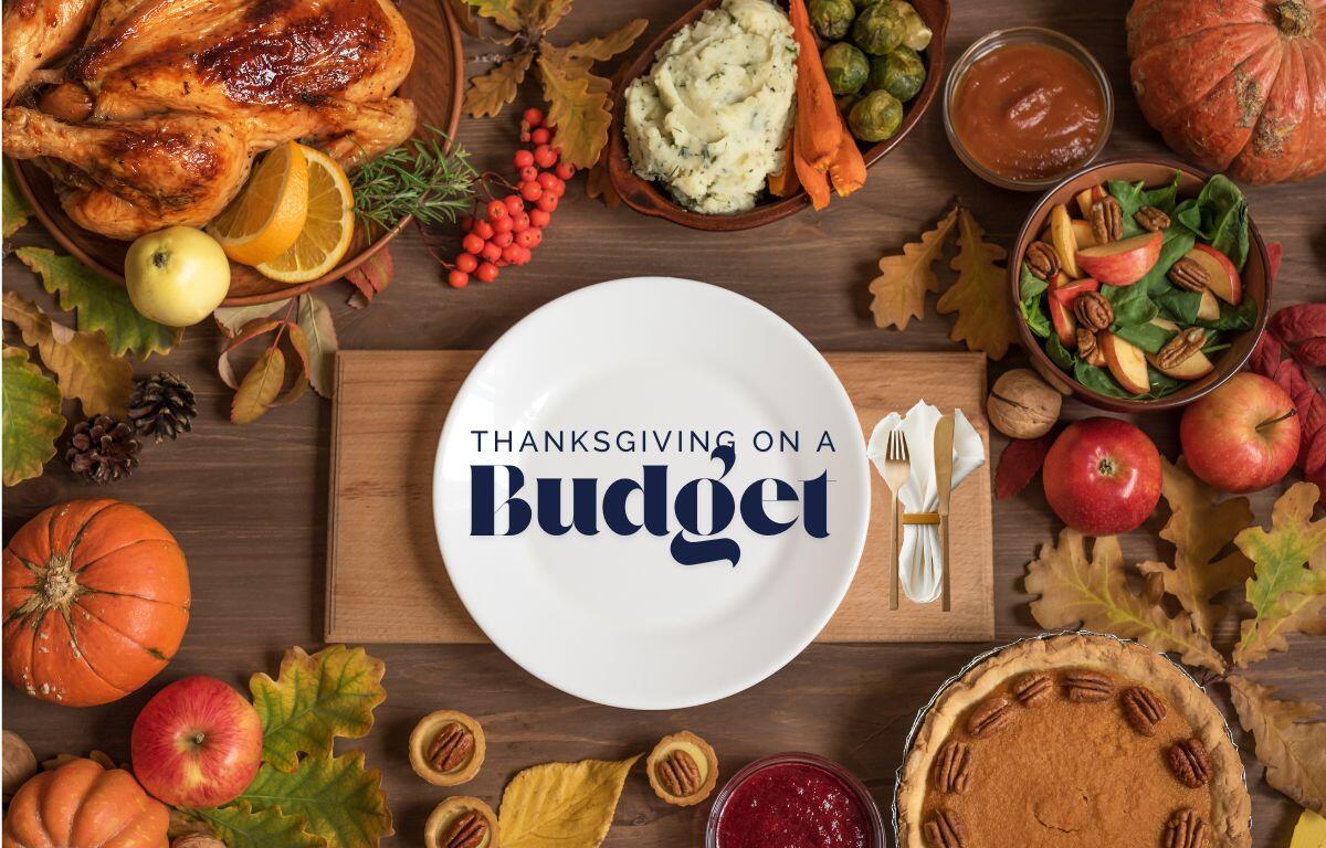 A Thanksgiving table filled with budget-friendly holiday foods, including a roasted chicken, mashed potatoes, vegetables, salad, cranberries, pie, pumpkins and apples, with a large white plate in the center displaying the text “Thanksgiving on a Budget.”