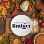 A Thanksgiving table filled with budget-friendly holiday foods, including a roasted chicken, mashed potatoes, vegetables, salad, cranberries, pie, pumpkins and apples, with a large white plate in the center displaying the text “Thanksgiving on a Budget.”