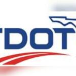 White background, blue lettering, outline of the State of Florida, and in the foreground and orange image to symbolize a road.