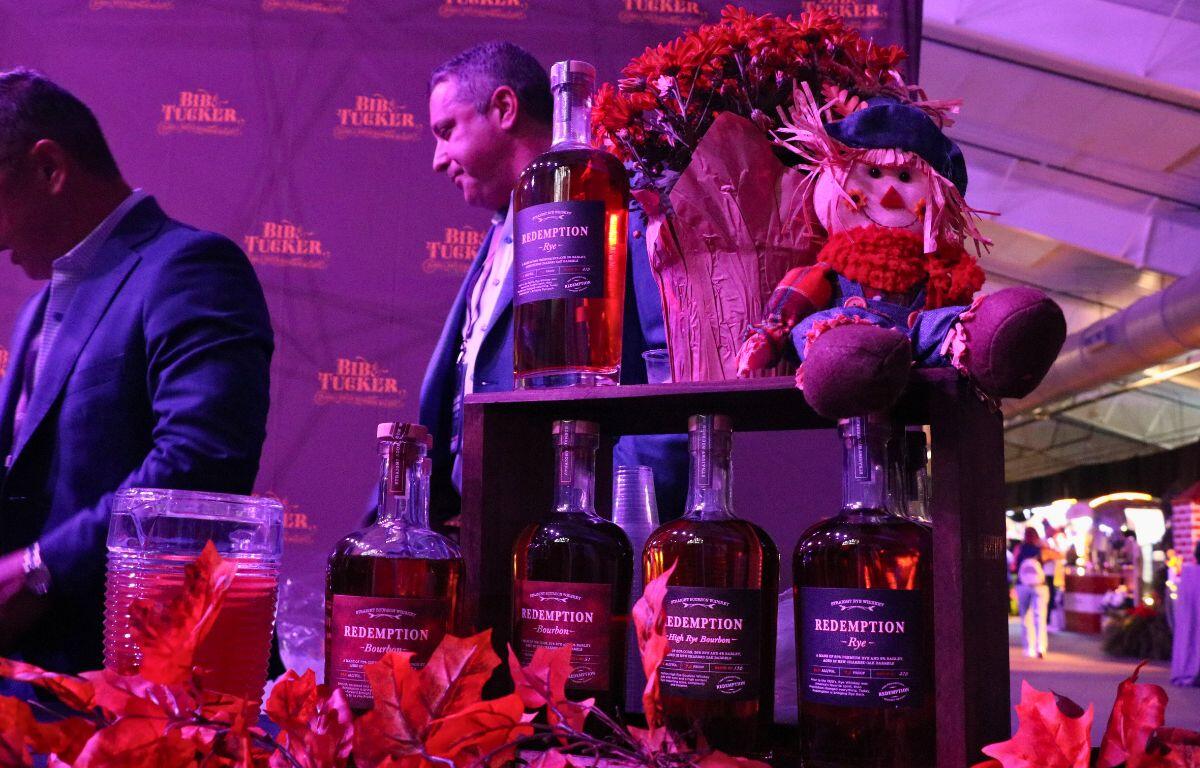 A table with fall decorations has a wooden display shelf with alcoholic beverages from Redemption Whiskey.