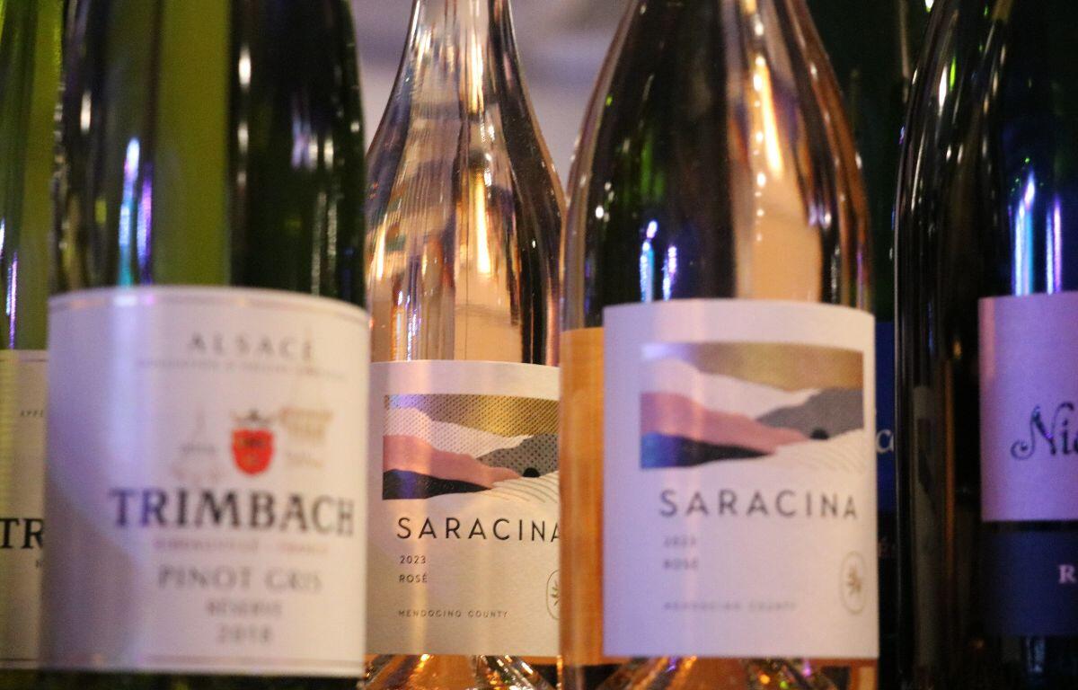 Multiple alcoholic beverages are lined up on a table with three blurred in the front and one clear in the back.