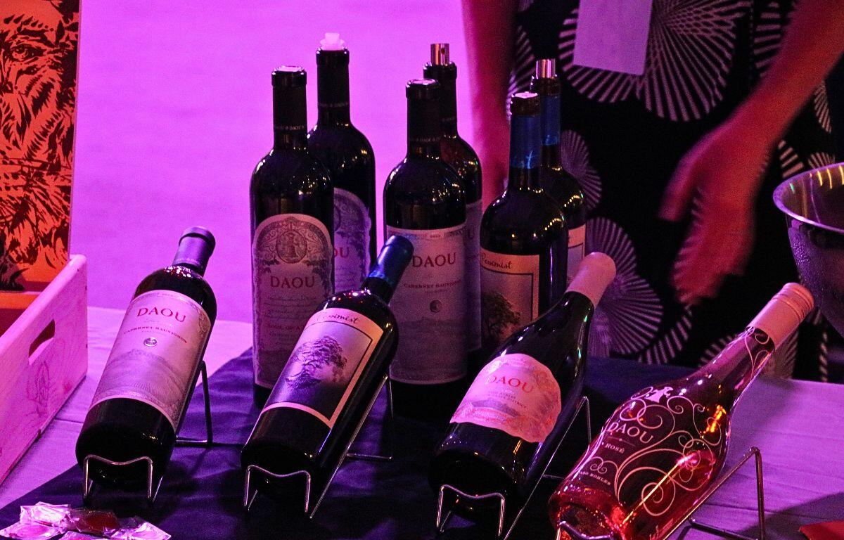 A variety of wine bottles displayed on a table with pink mood lighting.