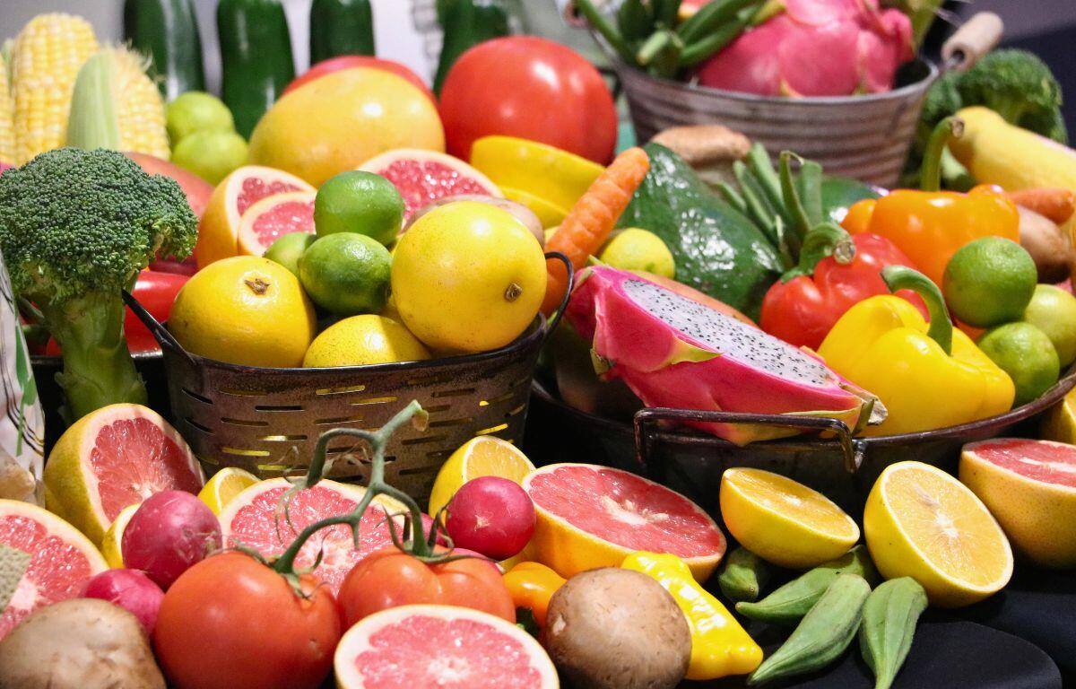 A variety of fruits and vegetables are displayed on a table with a black tablecloth.