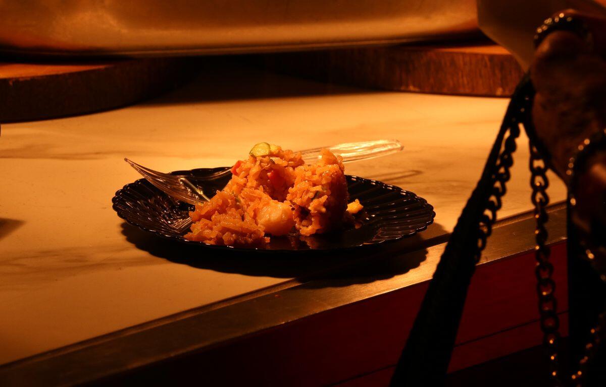 A black plate with a clear plastic fork has sample food made of rice and vegetables.