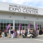 The World Equestrian Center Expo Center facade with purple feather flags advertising the Ocala Food and Wine Festival. Attendees await entry.